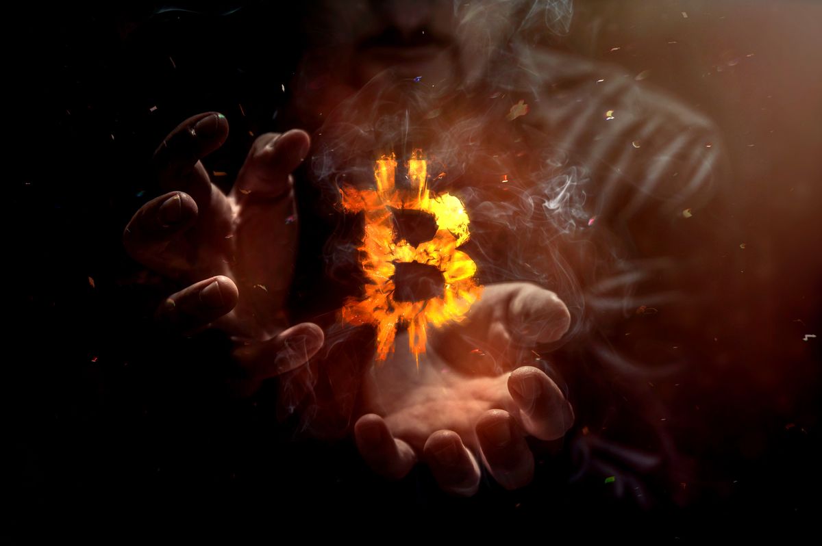 Burning symbol of bitcoin with man in the background. Conception of risk management in money trading at currency marketBurning symbol of bitcoin with man in the background. Conception of risk management in money trading at currency market