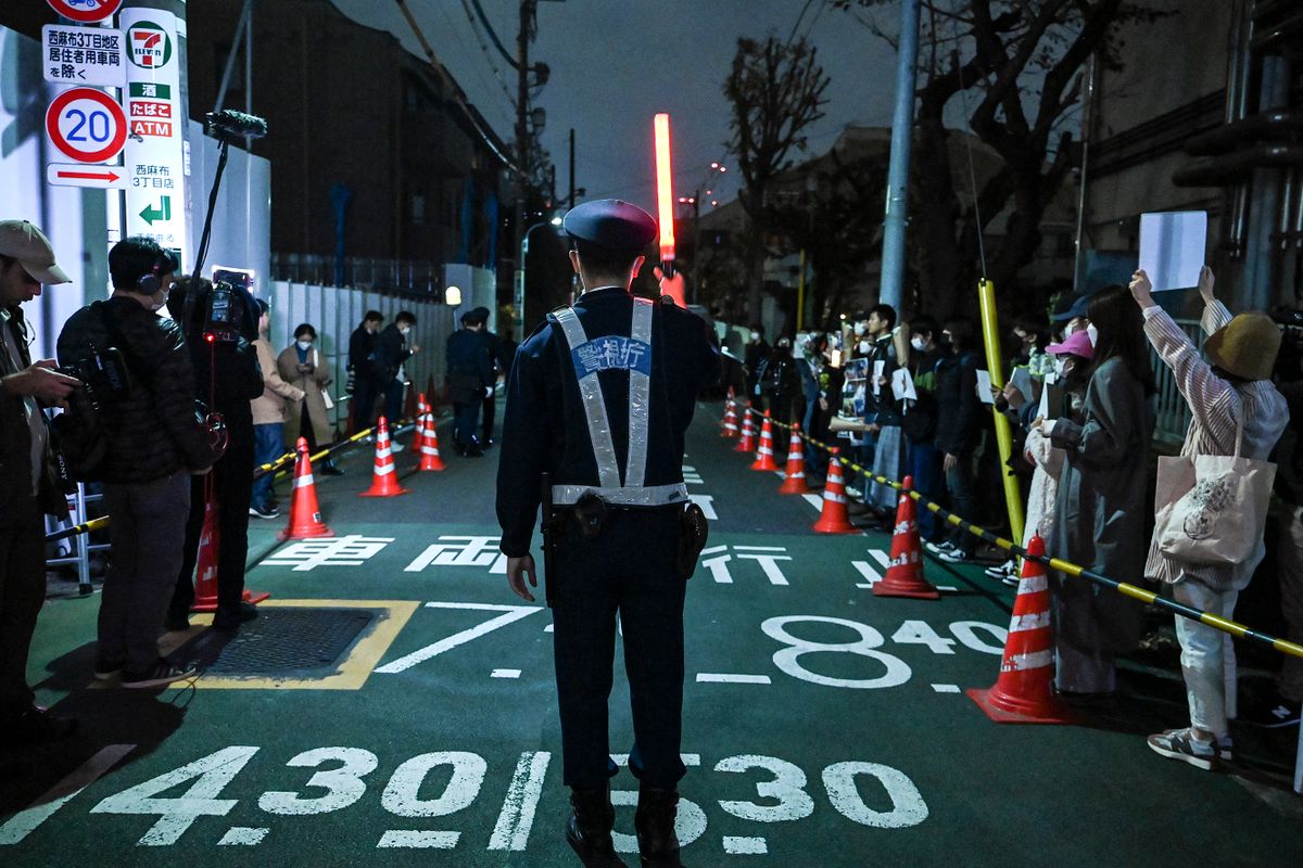 A Japanese policeman stands in the middle of the road as a group of protesters (R) hold a peaceful gathering down the street from the Chinese embassy in Tokyo on November 28, 2022, in support of demonstrations held in China over Beijing's Covid-19 restrictions. - Hundreds of people have taken to the streets in China's major cities in a rare outpouring of public anger against the state over its zero-Covid policy. (Photo by )