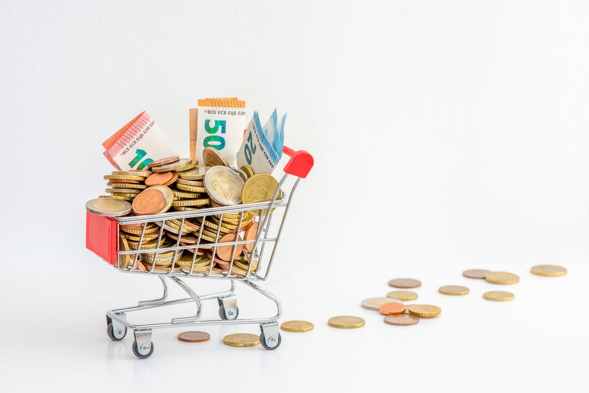 Europe: Shopping cart overflowing with cash (euro coins and banknotes). Concepts of rising prices, purchasing power and growing inflation in the euro zone. White background