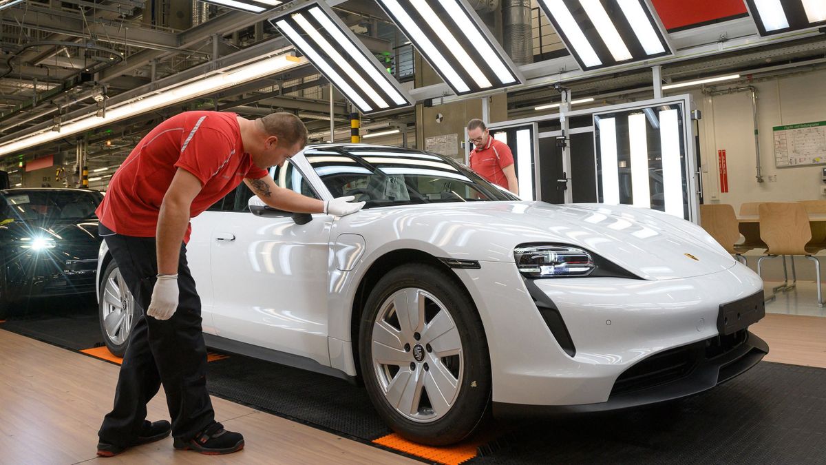 Employees of German car manufacturer Porsche AG inspect the quality of the varnish of Taycan full-electric sports cars under a light channel at the end of the assembly line at the production site in Stuttgart, southern Germany, on September 26, 2022.
