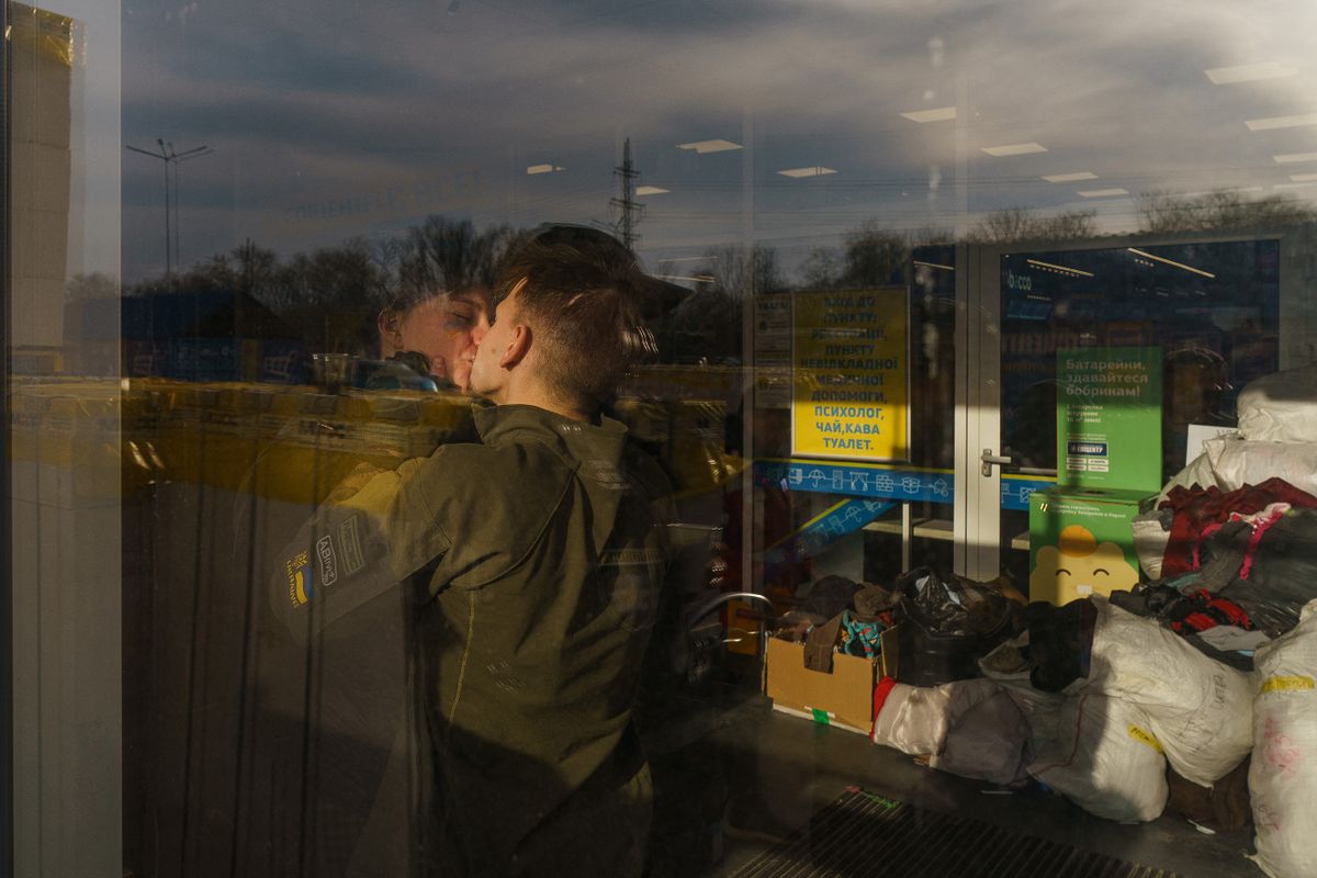 Lina and Vlad, both volunteers, kiss each other at the registration center in Zaporizhzhia, on March 29, 2022.  - A humanitarian convoy leaving the devastated southern port of Mariupol -- including ambulances carrying wounded children -- arrived in Zaporizhzhia on March 27, 2022. 