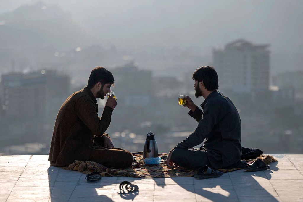 Afghan men drink tea at Nadir Khan hilltop overlooking Kabul on November 23, 2022. (Photo by Wakil KOHSAR / AFP)