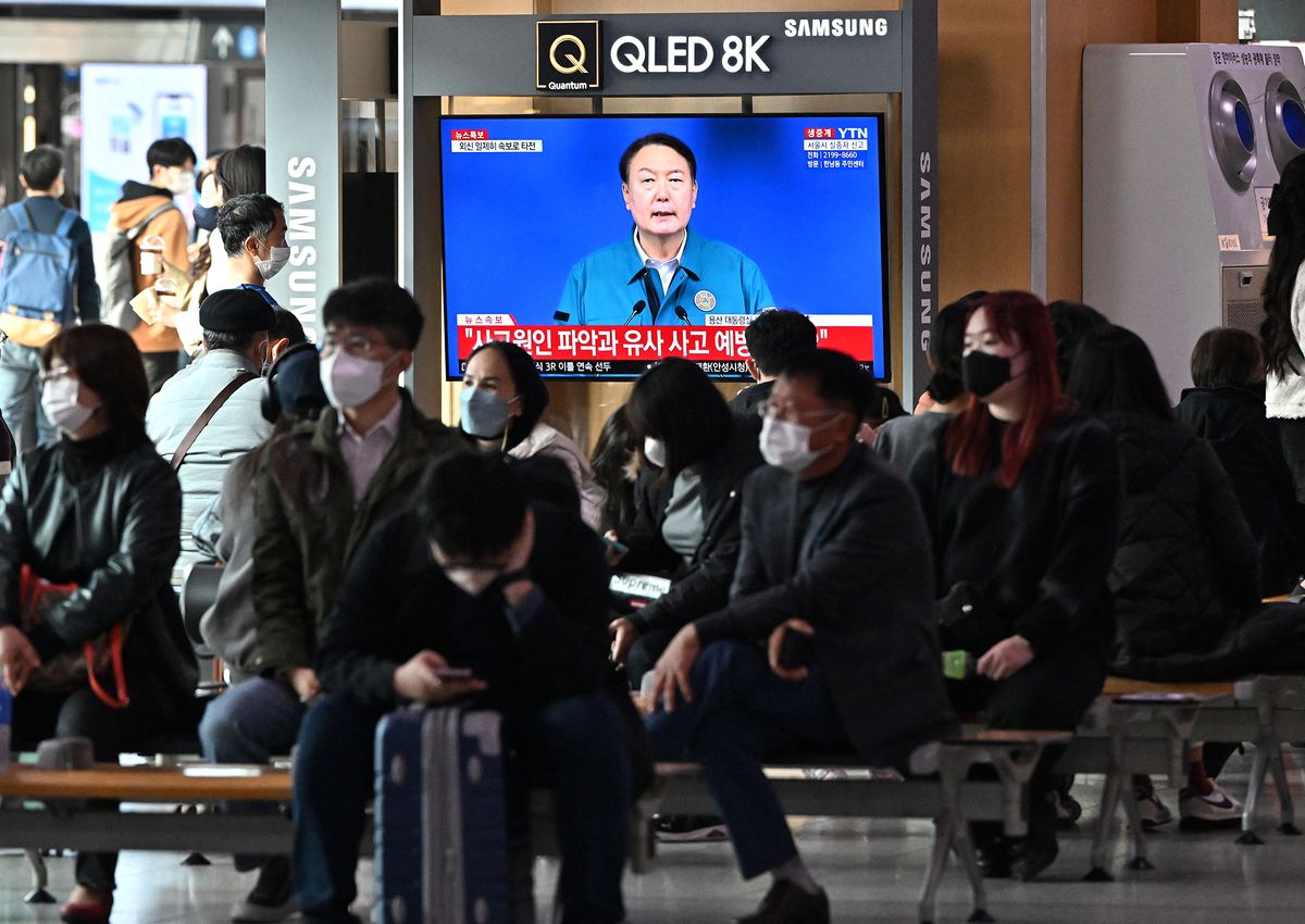 People watch a television news programme broadcasting live footage of South Korean President Yoon Suk-yeol delivering a speech on the deadly Halloween stampede, at a railway station in Seoul on October 30, 2022. - At least 149 people were killed and scores more were injured in a stampede at a packed Halloween event in central Seoul late on October 29, officials said, in one of South Korea's worst peacetime accidents.