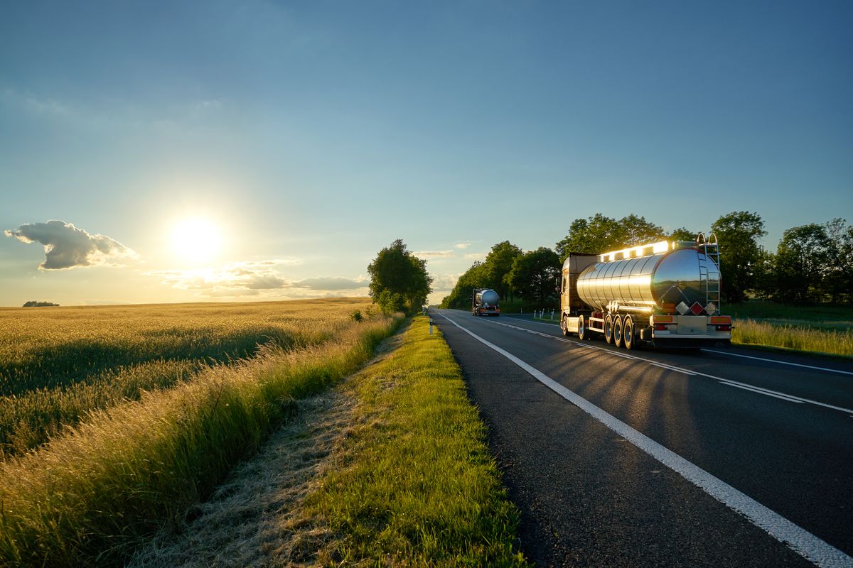 Trucks with chrome tank driving on road at sunset., Trucks with chrome tank driving on asphalt road along the corn field at sunset. The landscape and the road are mirrored on a silver tanker., MOL, fuel, trucks, mol, üzemanyag, benzinkút, kutak, 