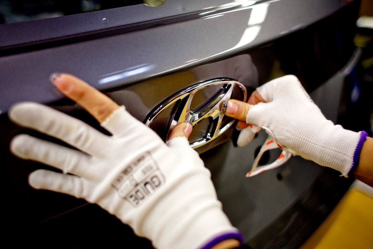 Automobile Production At Czech Republic's Hyundai Motor Co. Plant, 
An employee places a badge onto the trunk of a Hyundai automobile during the final stages of manufacture at the Hyundai Motor Co. plant in Nosovice, Czech Republic, on Tuesday, Dec. 3, 2013. Exports, which account for about 80 percent of Czech GDP, are led by manufacturers including the factories of carmakers Hyundai Motor Co., Volkswagen AG's Skoda Auto AS, Peugeot SA and Toyota Motor Corp. Photographer: Martin Divisek/Bloomberg via Getty Images
