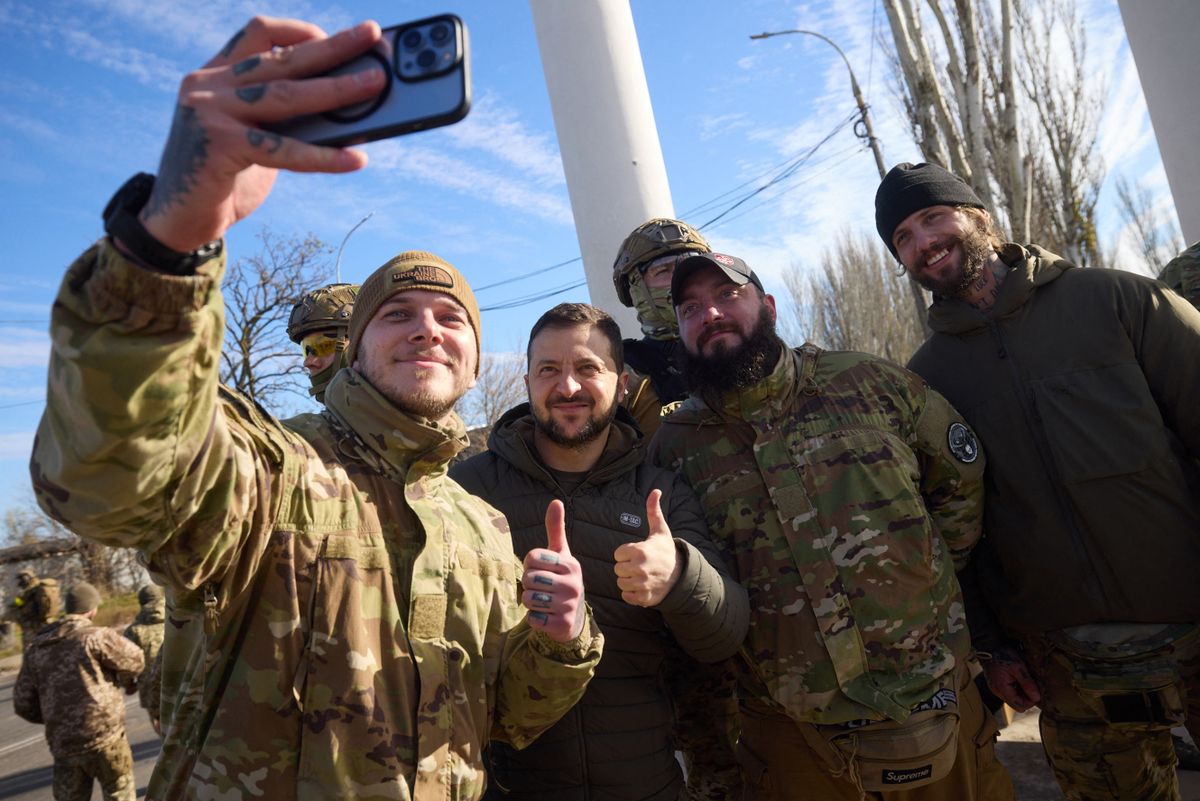 This handout photograph taken and released by Ukrainian Presidential press service on November 14, 2022, shows Ukrainian President Volodymyr Zelensky (2ndL) posing for a selfie with Ukrainian servicemen during his visit to the newly liberated city of Kherson, following the retreat of Russian forces from the strategic hub. 