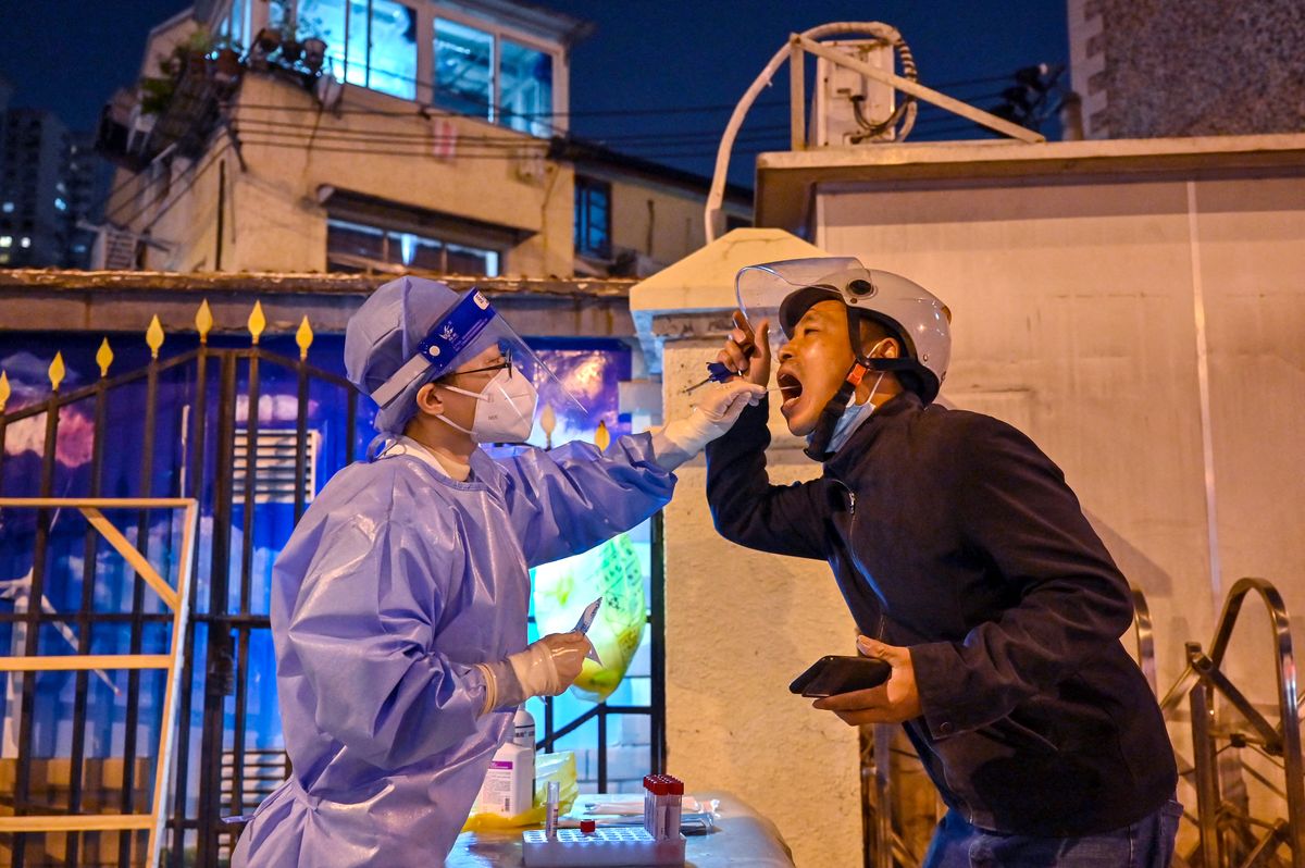 A health worker takes a swab sample from a man to test for the Covid-19 coronavirus on a street in the Jing'an district in Shanghai, on November 1, 2022. (Photo by Hector RETAMAL / AFP)