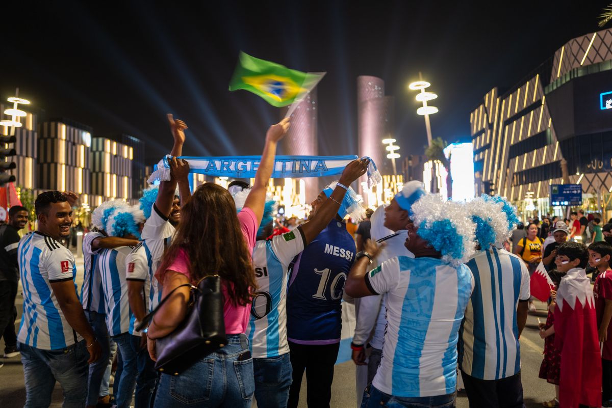 FIFA World Cup Qatar 2022 Previews, DOHA, QATAR - 17 November :  A woman waves the flag of Brazil over the heads of fans of Argentina having their picture taken in Lusail Boulevard ahead of the FIFA World Cup Qatar 2022 at  on November 17, 2022 in Doha, Qatar. (Photo by Matthew Ashton - AMA/Getty Images)