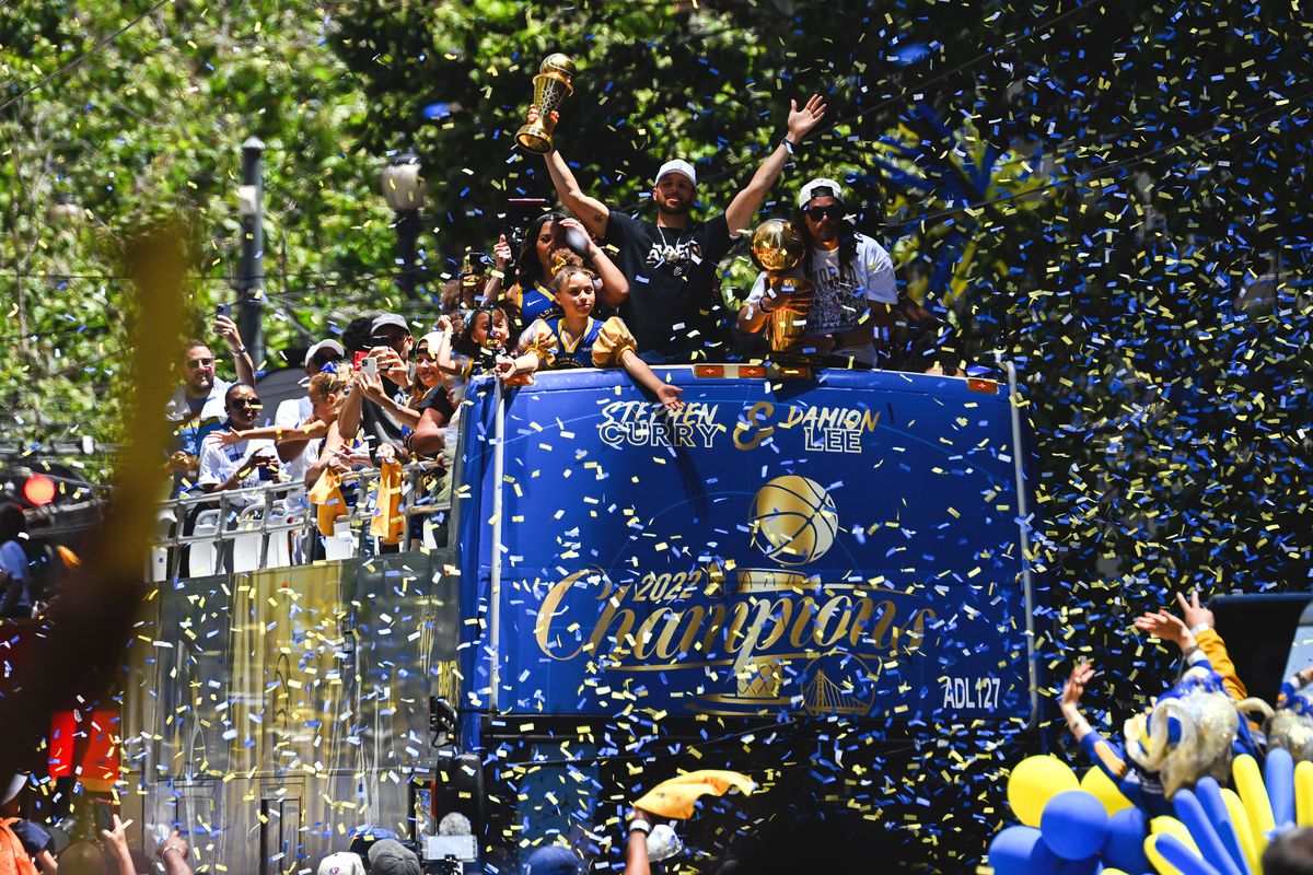 Stephen Curry and Damion Lee hold trophies as they wave from a confetti-covered double-decker bus as basketball fans cheer them on during the Golden State Warriors NBA Championship victory parade on Market Street on June 20, 2022 in San Francisco, California. - Tens of thousands of fans poured onto the streets of San Francisco on Monday to salute the victorious Golden State Warriors as the team celebrated its fourth NBA championship in eight seasons with an open-top bus parade. (Photo by Patrick T. FALLON / AFP)