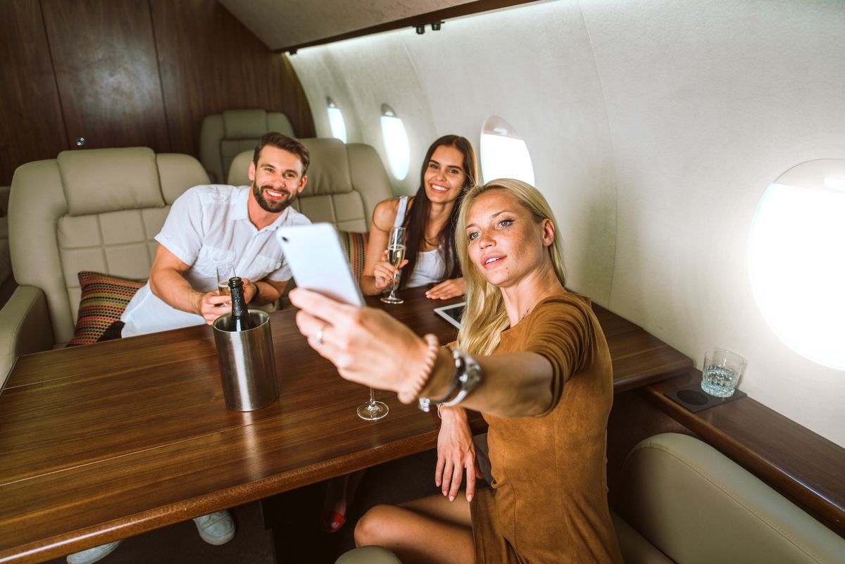 Beautiful Woman Taking Selfie Inside Airplane Group of friends going on vacation with a private jet