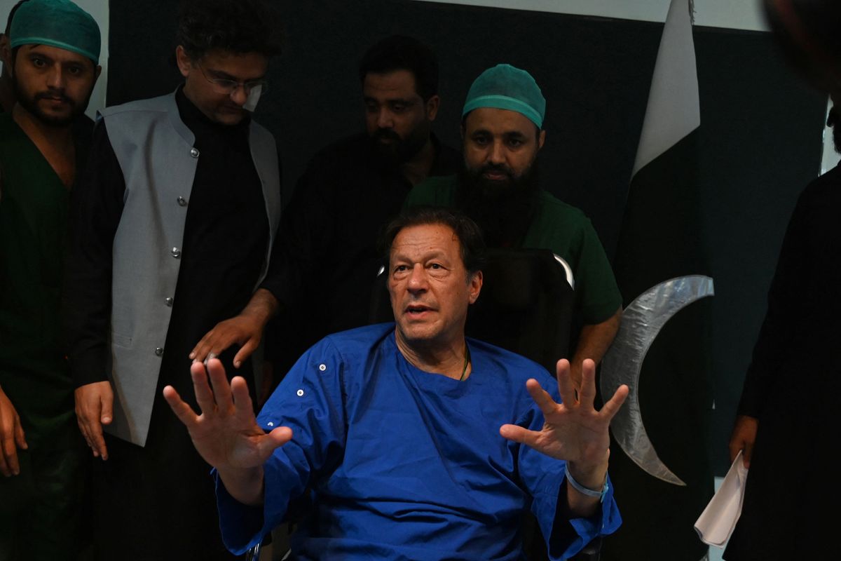 Pakistani paramedics move Pakistan's former prime minister Imran Khan as he sits in a wheelchair, after speaking to media representatives at a hospital in Lahore on November 4, 2022,  a day after an assassination attempt on him during his long march near Wazirabad. - Former Pakistan prime minister Imran Khan was recovering in hospital on November 4 after a gunman shot him in the leg, with his supporters vowing the assassination attempt will not derail his "long march" bid to return to power. 