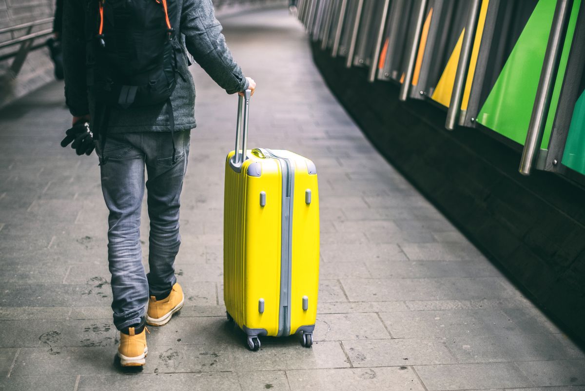 Close up of young man walking with luggage