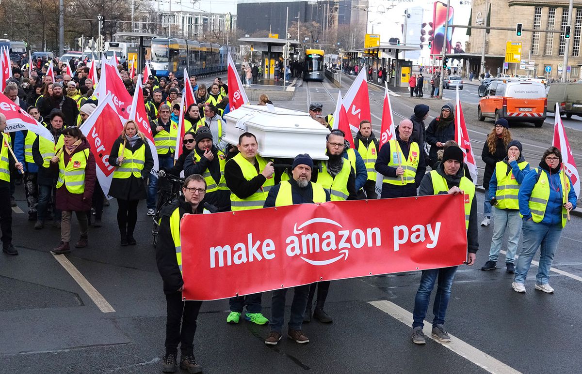 Strike at Amazon, 25 November 2022, Saxony, Leipzig: Participants of a demonstration of the trade union Verdi walk with flags and carry a banner with the inscription "Make Amazon pay" and a coffin. About 200 employees of the online mail order company Amazon protested for better working conditions and adequate pay. Photo: Sebastian Willnow/dpa (Photo by SEBASTIAN WILLNOW / DPA / dpa Picture-Alliance via AFP)