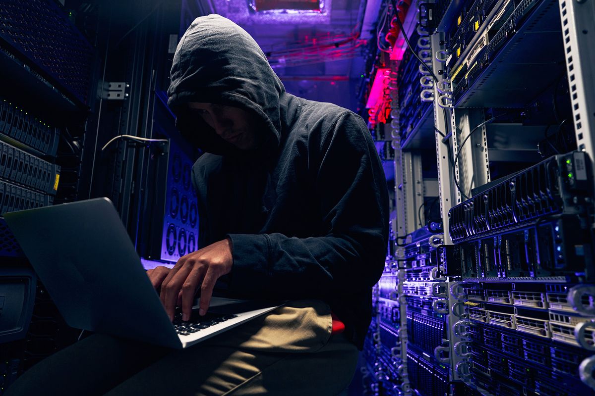 Hacker,Seated,In,Server,Room,Launching,Cyberattack,On,Laptop