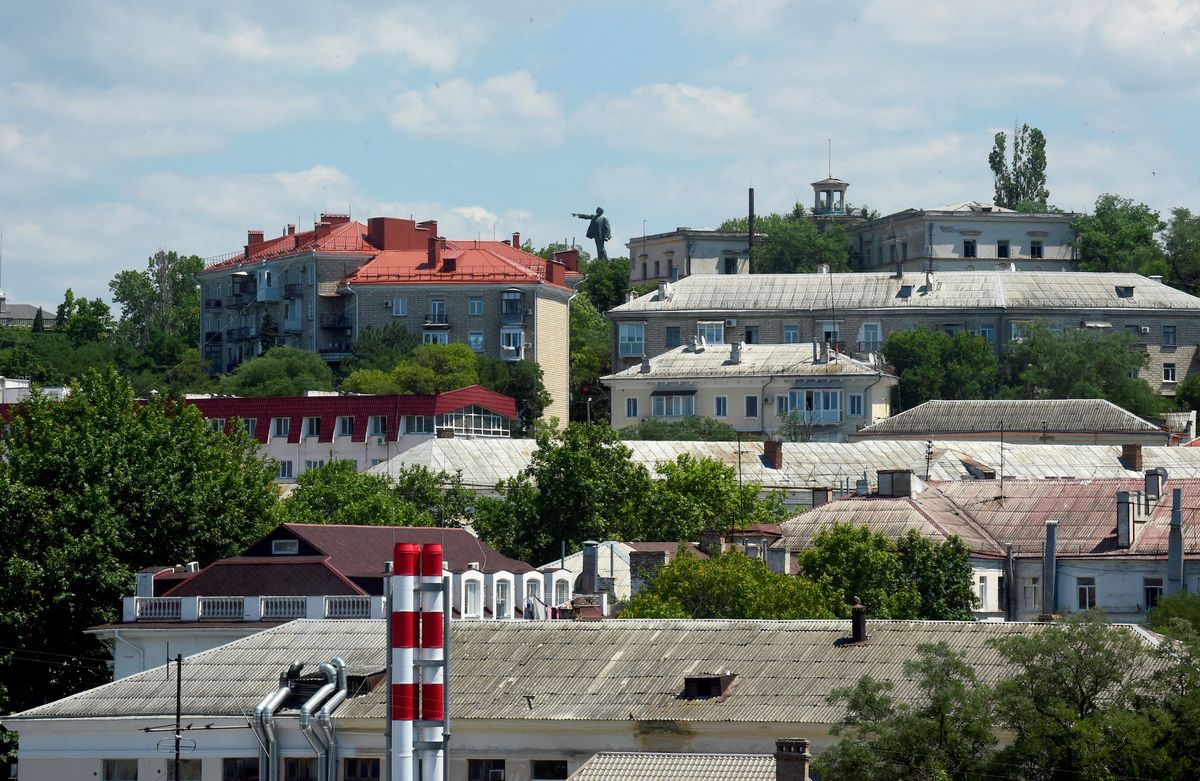 A monument to the Soviet State founder Vladimir Lenin sits on a hill behind residential buildings in Sevastopol, the largest city on the Crimean Peninsula and its most important port and naval base, on July 15, 2022. - Tourism in Crimea has fallen sharply in a region under Russian control, with beaches and other destinations only half full as visitors stay away due to fears and uncertainties over the ongoing Russian military action in Ukraine. Russian soldiers now stroll along Sevastopol's streets and tourist kiosks sell Russian flags and military insignia. (Photo by Olga MALTSEVA / AFP) UKRAINE-RUSSIA-CONFLICT-CRIMEA-TOURISM-LEISURE, orosz, krím, ingatlan, 