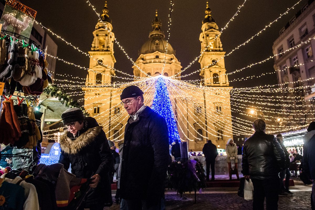 Shoppers browse alpaca wool products at a Christmas market as an illuminated Christmas tree stands in front of St. Stephen's Basilica in Budapest, Hungary, on Monday, Dec. 7, 2015. Hungary GDP growth slowed less than forecast to 2.4% year on year in the third quarter.