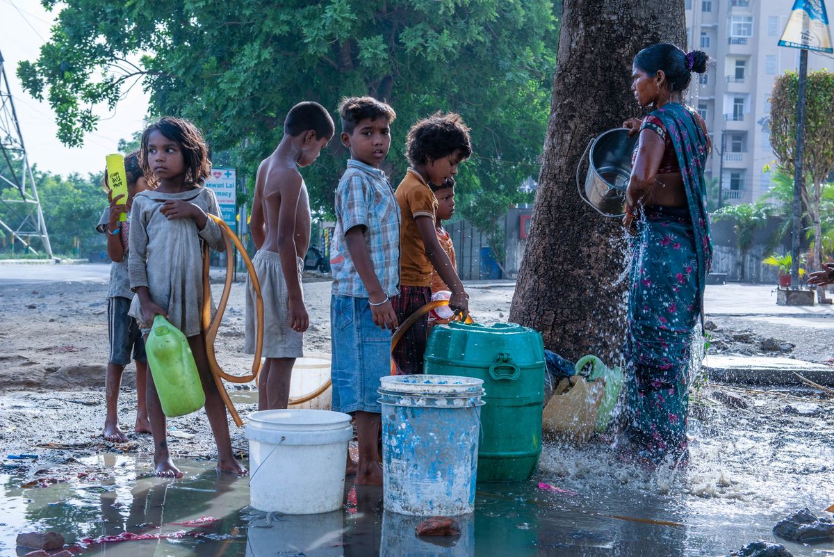 GHAZIABAD, UTTAR PRADESH, INDIA - 2022/06/12: A child fills a container with water from a roadside water pipeline leakage in Ghaziabad. Slum children collect drinking and daily use water from a roadside water pipe leakage. (Photo by /SOPA Images/LightRocket via Getty Images)