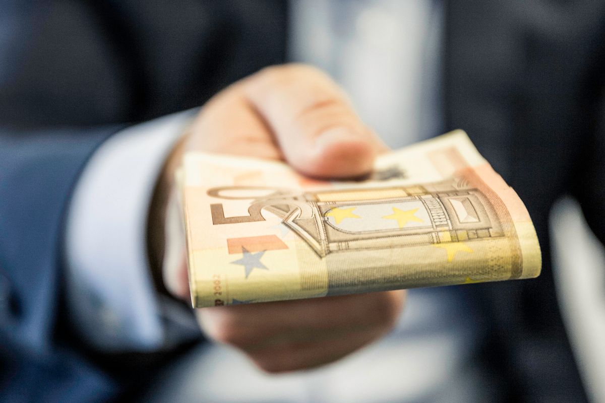 Close up of businessmans hand handing folded fifty euro notes, eu, money, 