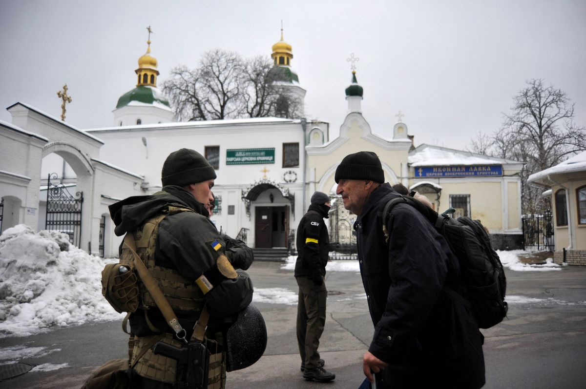 A Ukraine's Security Service (SBU) serviceman talks with a visitor in front of Kyiv Pechersk Lavra monastery in Kyiv on November 22, 2022, amid the Russian invasion of Ukraine. - Ukraine's security service on November 22, said it carried out a raid on a historic Orthodox monastery in the capital Kyiv over suspected "activities" of Russian agents.Located south of Kyiv's city centre, the 11th century Kyiv Pechersk Lavra is a UNESCO World Heritage site and seat of a branch of Ukraine's Orthodox Church that was formerly under Moscow's jurisdiction. 