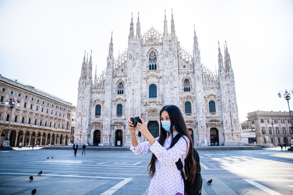 Asian tourist woman taking pictures with camera during coronavirus in duomo Milan