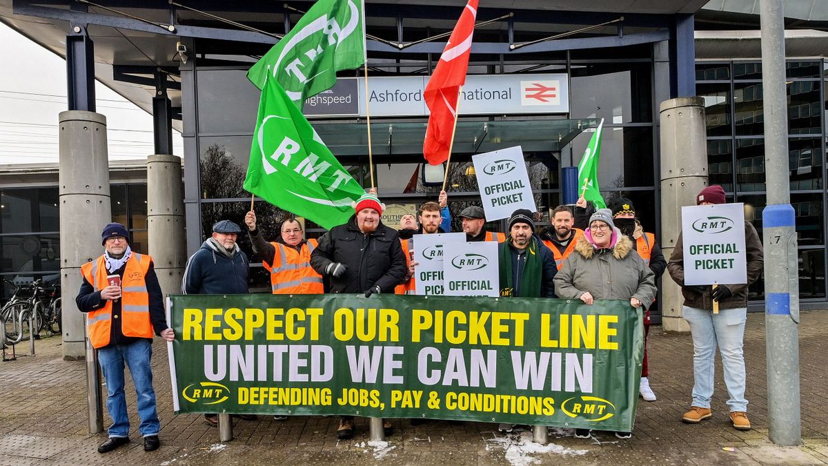 KENT, UNITED KINGDOM - DECEMBER 13: Rail workers hold banners and union flags during the strike over pay, job security and working conditions outside the Ashford International railway station in Kent, United Kingdom on December 13, 2022. Stuart Brock / Anadolu Agency (Photo by Stuart Brock / ANADOLU AGENCY / Anadolu Agency via AFP)