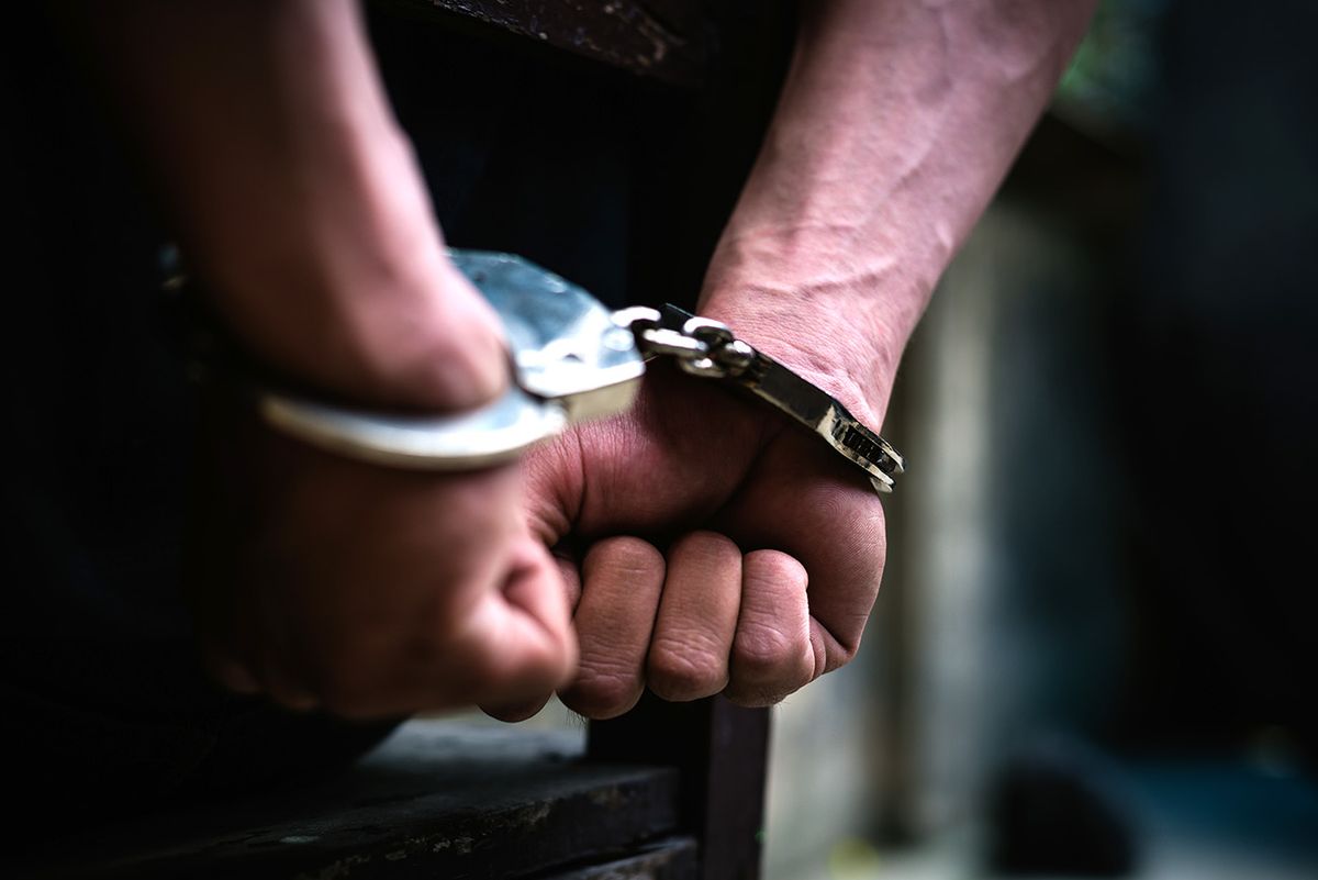 Cropped Hand Of Handcuffs,
Man on the chair in Handcuffs. Rear view and Closeup ,Men criminal in handcuffs arrested for crimes. With hands in back,boy  prison shackle in the jail violence concept.