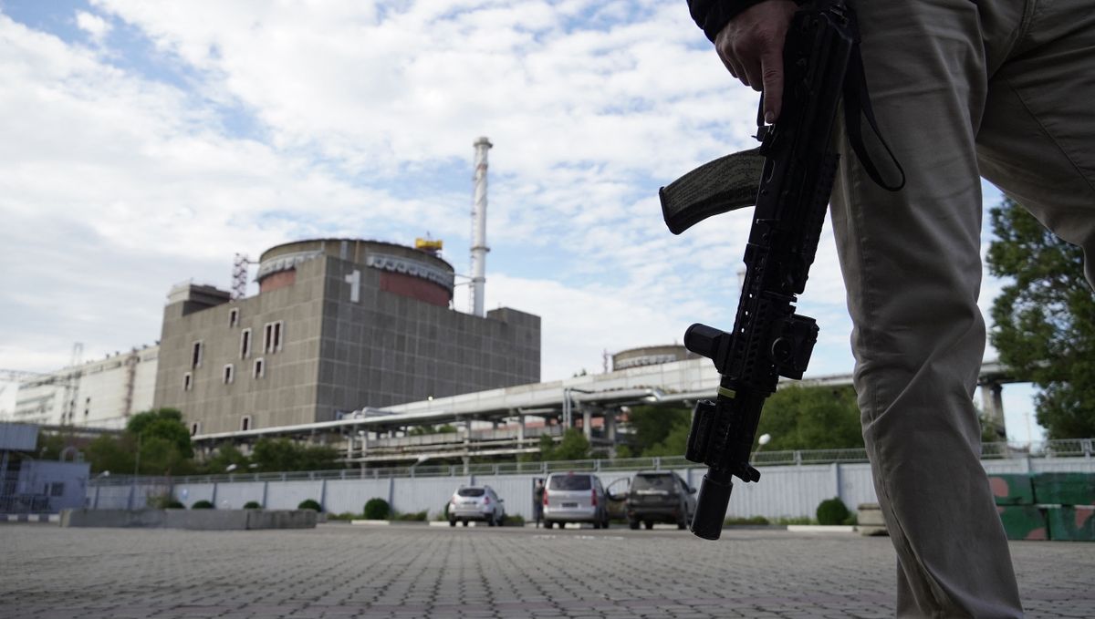 This photo taken on September 11, 2022 shows a security person standing in front of the Zaporizhzhia Nuclear Power Plant in Enerhodar (Energodar), Zaporizhzhia Oblast, amid the ongoing Russian military action in Ukraine. - The Zaporizhzhia Nuclear Power Station in southeastern Ukraine is the largest nuclear power plant in Europe and among the 10 largest in the world. 