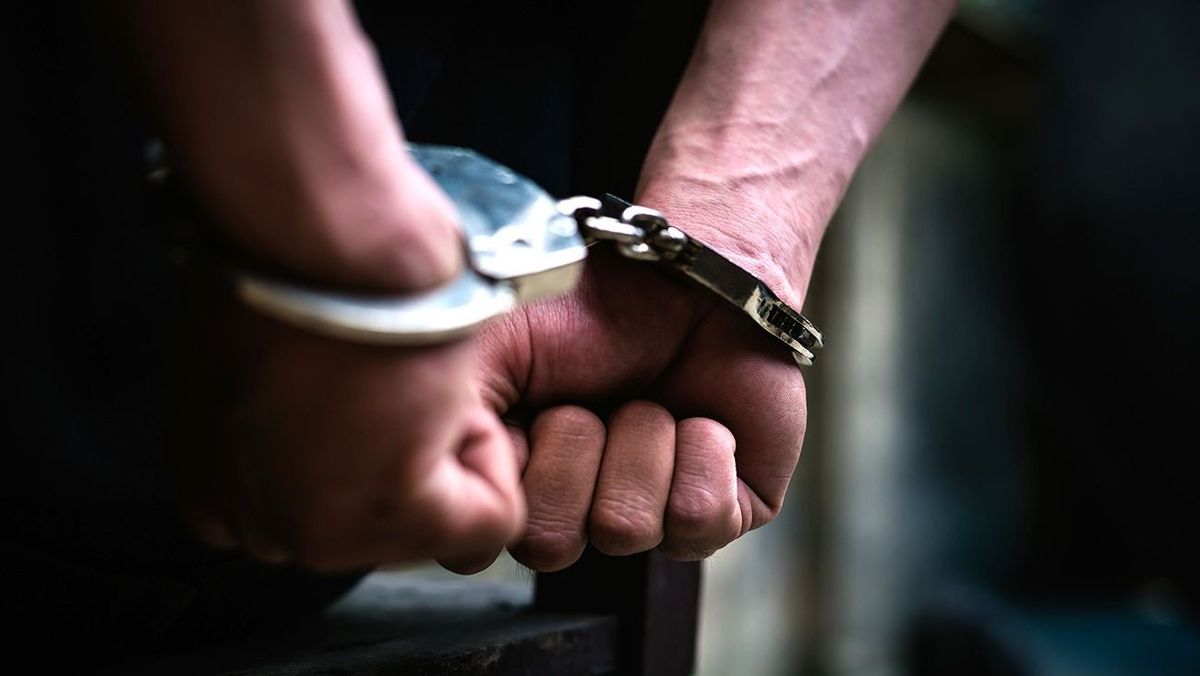 Cropped Hand Of Handcuffs,
Man on the chair in Handcuffs. Rear view and Closeup ,Men criminal in handcuffs arrested for crimes. With hands in back,boy  prison shackle in the jail violence concept.