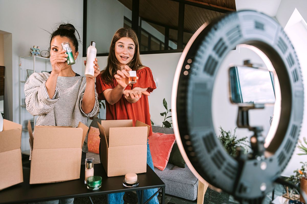 Mother and daughter showing beauty products while filming at home workshop