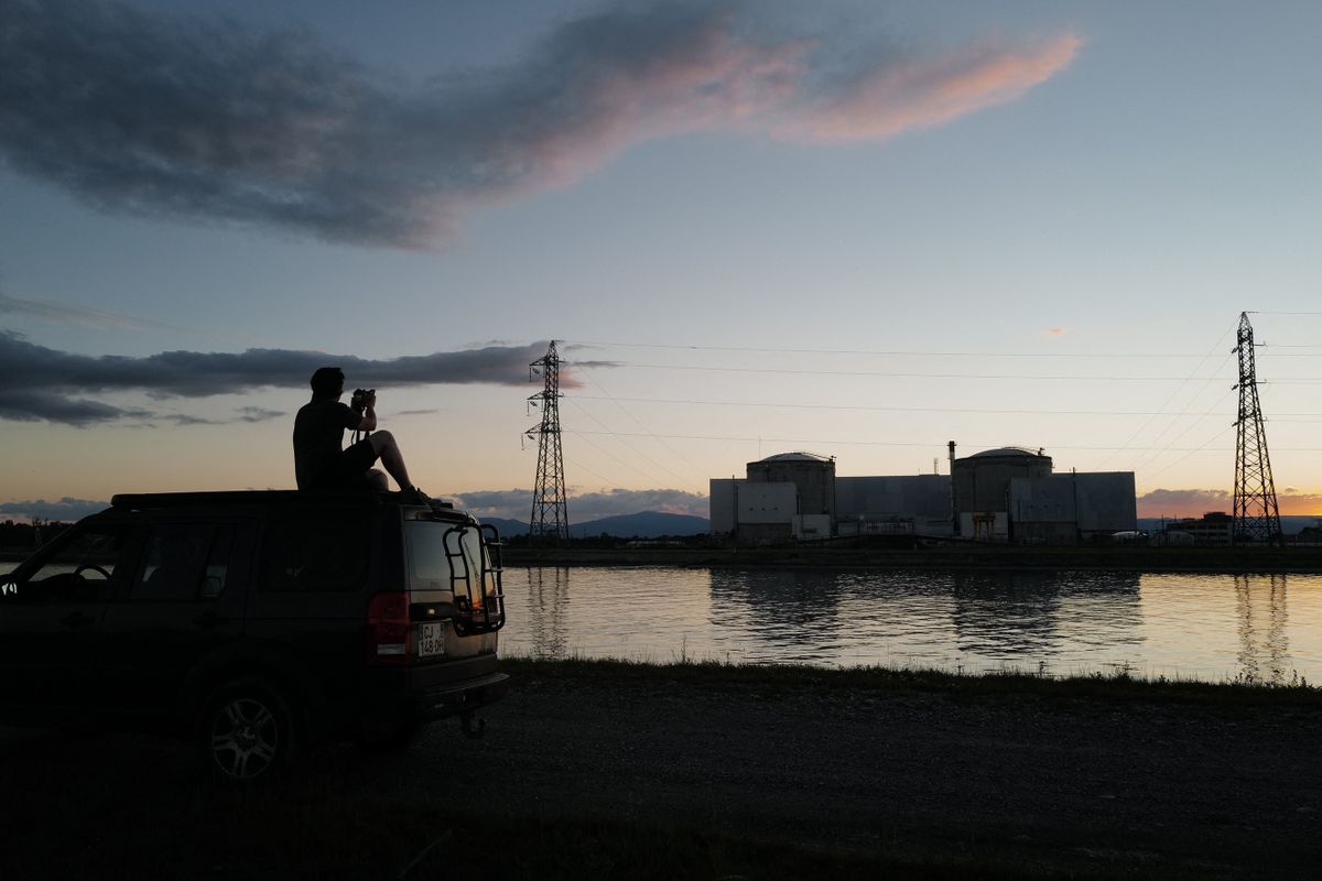 A man takes pictures of the nuclear powerplant in Fessenheim, eastern France, on June 29, 2020 as an operation to switch off this French oldest nuclear plant got under way today, ending four decades of output that built the local economy but also attracted cross-border controversy. - The second and last reactor of the plant at Fessenheim in the east of France -- opened in 1977 and three years over its projected 40-year life span -- should go offline shortly before midnight, said state-owned power company EDF. 