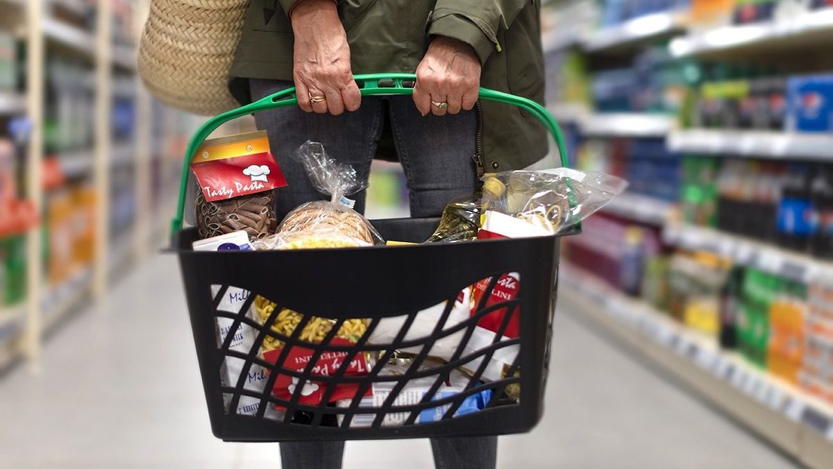 Woman shopping at a slovakian supermarket, she is carrying full shopping basket, close-up. Woman shopping at the supermarket, she is carrying full shopping basket