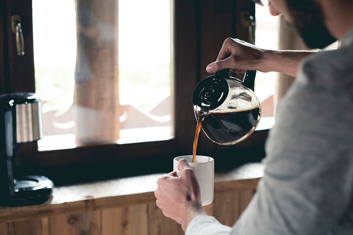 Young man pouring coffee into cup at home, kávé, fogyaztás, szokás, 