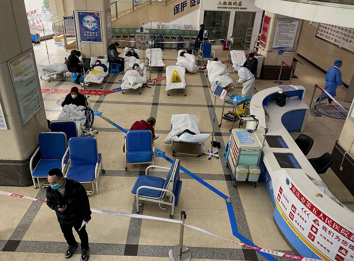 A man stands in front of a cordoned-off area, where Covid-19 coronavirus patients lie on hospital beds, in the lobby of the Chongqing No. 5 People's Hospital in China's southwestern city of Chongqing on December 23, 2022. (Photo by Noel CELIS / AFP)