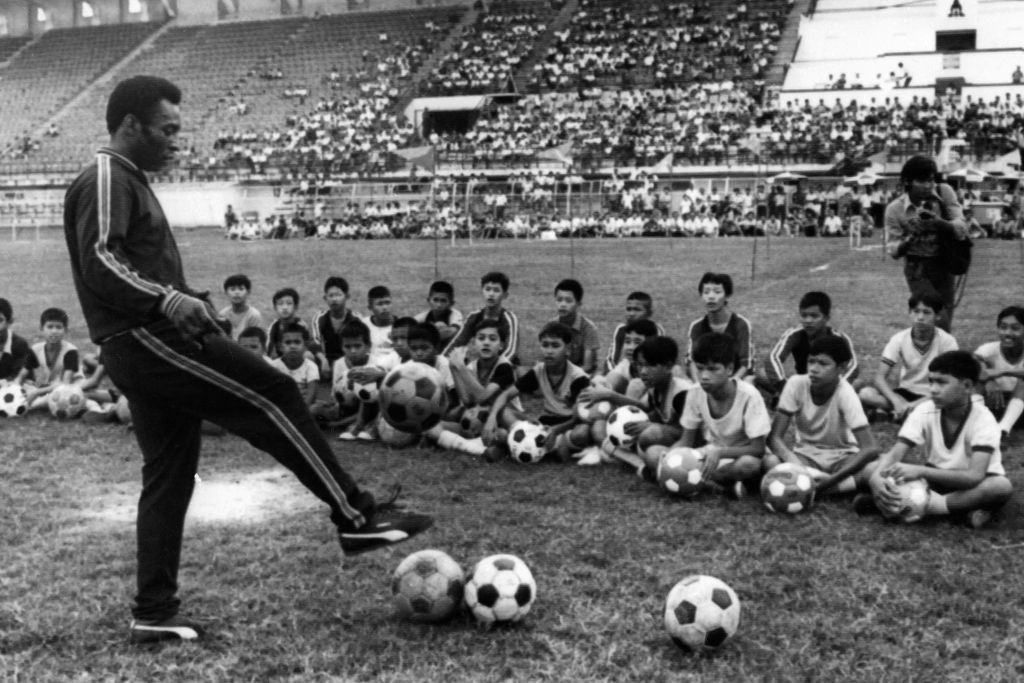 (FILES) In this file photo taken on December 06, 1974 in Bangkok shows Brazilian football player Pelé during a training session with young boy as part of a commercial trip in Thailand. - Brazilian football icon Pele, widely regarded as the greatest player of all time and a three-time World Cup winner who masterminded the 'beautiful game', died on December 29, 2022 at the age of 82, after battling kidney problems and colon cancer. (Photo by AFP)