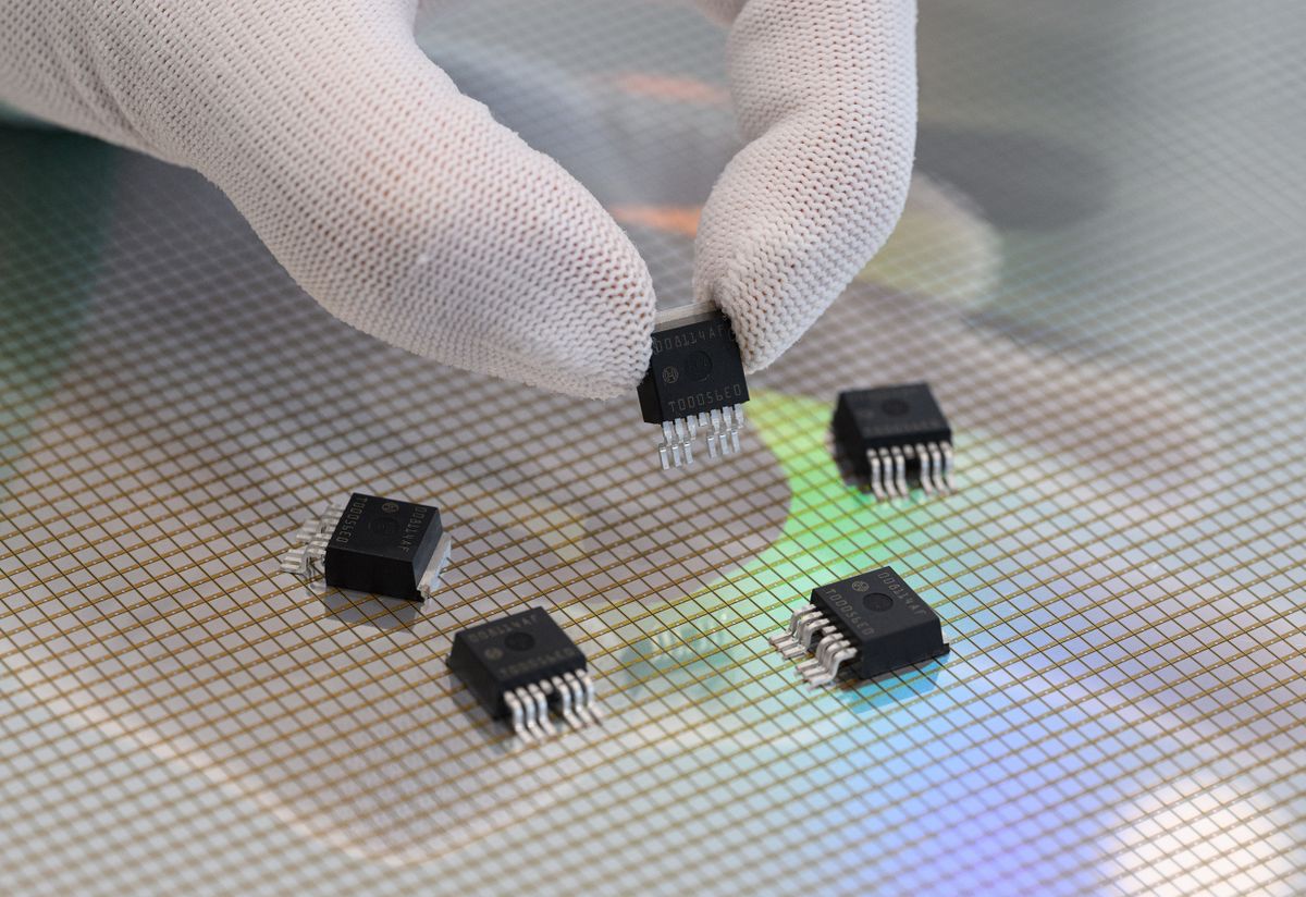 13 July 2022, Saxony, Dresden: An associate presents micromechanical sensors over a 300-millimeter wafer at Bosch's semiconductor factory before the start of "Bosch Tech Day." 