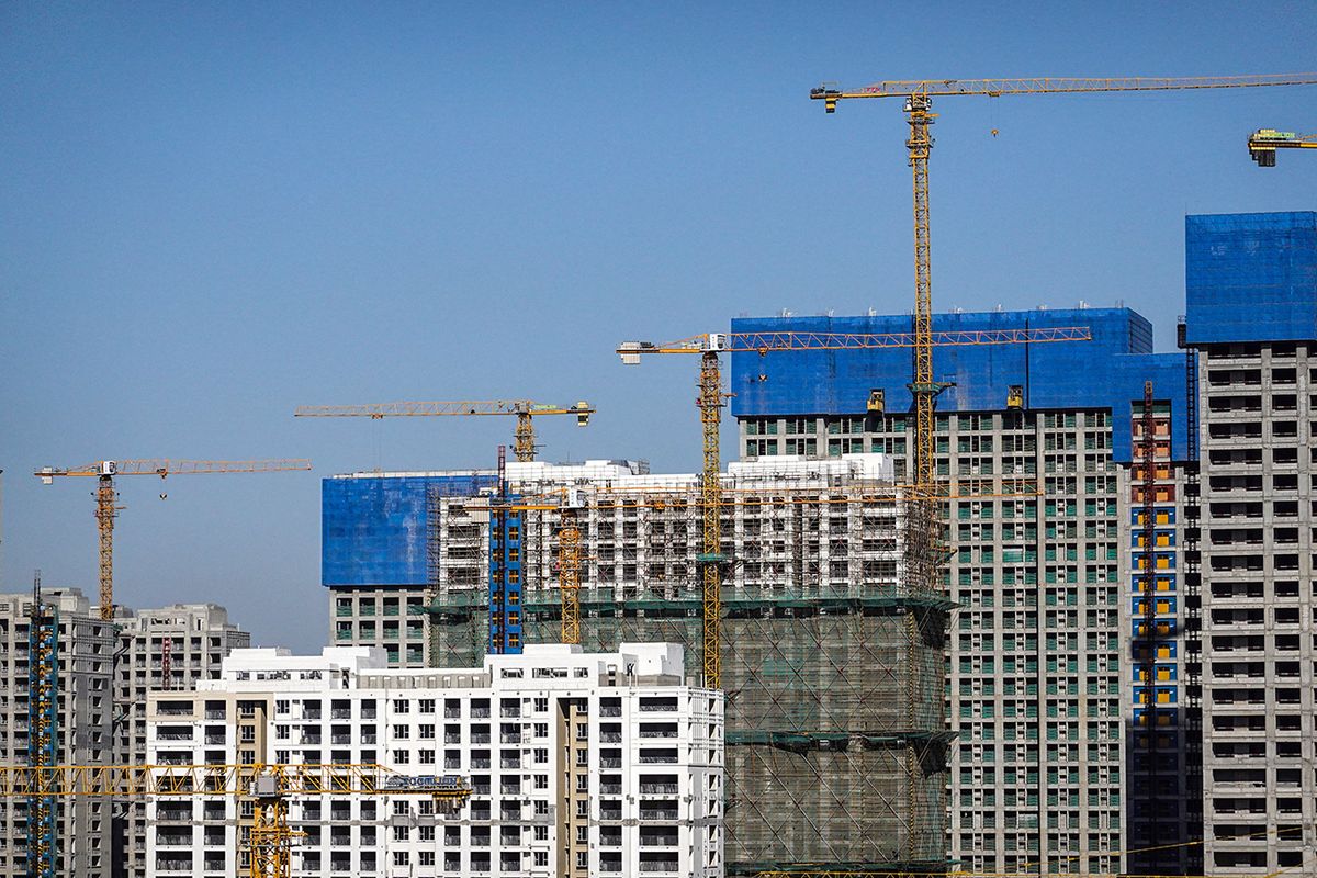 Tower cranes work at a construction site with residential CHANGZHOU, CHINA - 2022/12/18: Tower cranes work at a construction site with residential buildings in the background. (Photo by Sheldon Cooper/SOPA Images/LightRocket via Getty Images)
