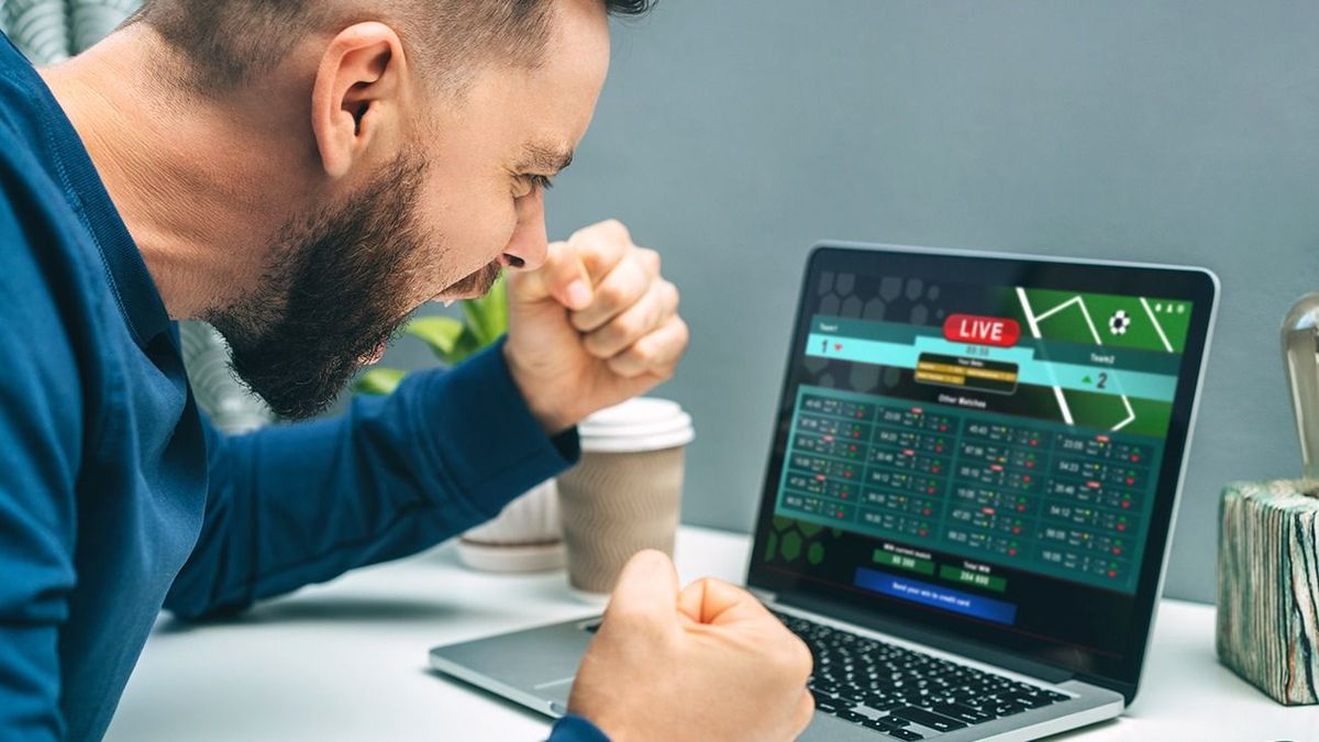 Male,Fan,Watching,Football,Play,Online,Broadcast,On,His,Laptop, Male fan watching football play online broadcast on his laptop, cheering for favourite team and betting at bookmaker's website. Lucky man celebrating victory after winning jackpot in online casino.