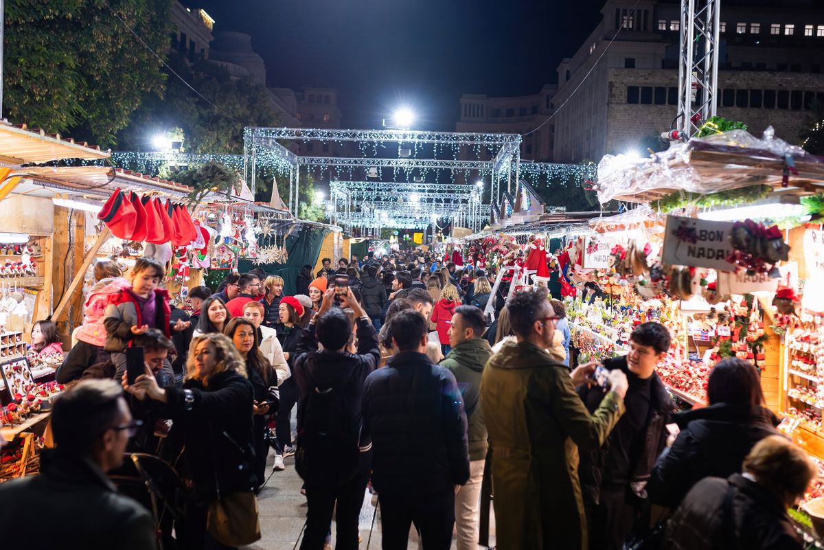 BARCELONA, SPAIN - 2022/11/26: Tourists and shoppers are seen in the popular Christmas market "Fira de Santa Llucia" at night. The historic market is one of the oldest in Europe and has been held in Barcelona since 1786 on Avinguda de la Catedral. The Barcelona City administration has reduced the quantity of lights and the illumination time of their Christmas lights due to the increased costs of energy caused by the Russia-Ukraine war.