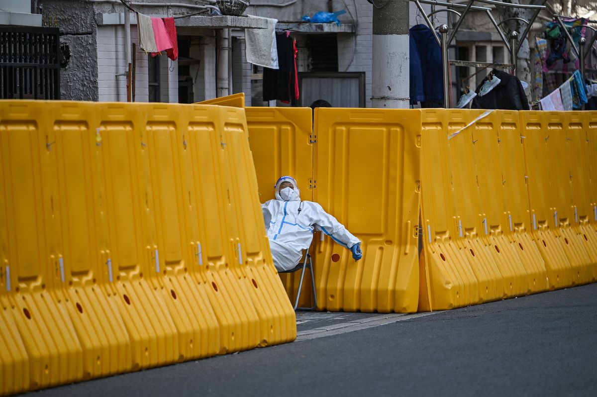 -- AFP PICTURES OF THE YEAR 2022 --A worker, wearing a protective gear, guards the entrance to a neighborhood in lockdown as a measure against the Covid-19 coronavirus, in Jing'an district, in Shanghai on March 29, 2022. (Photo by  / AFP) / AFP PICTURES OF THE YEAR 2