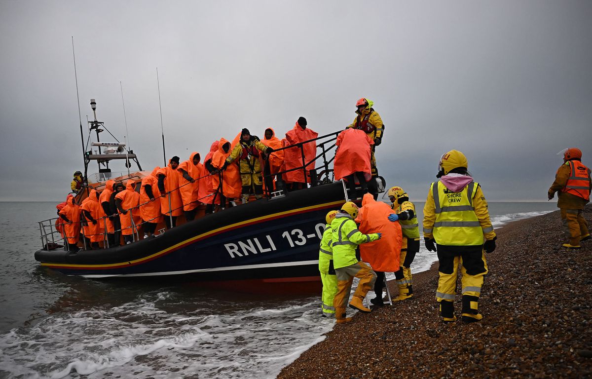 Migrants, picked up at sea attempting to cross the English Channel, are helped ashore from an Royal National Lifeboat Institution (RNLI) lifeboat, at Dungeness on the southeast coast of England, on December 9, 2022.