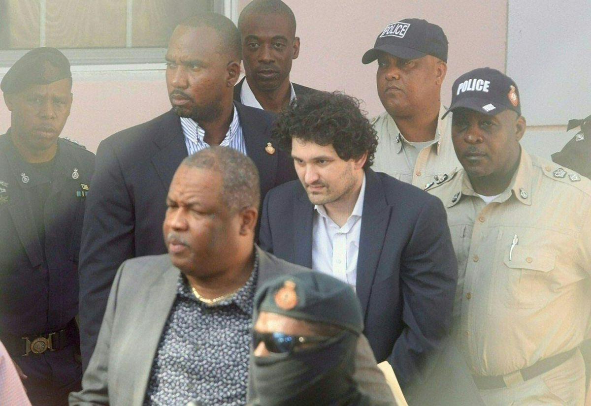 FTX founder Sam Bankman-Fried (C) is led away handcuffed by officers of the Royal Bahamas Police Force at the Nassau, Bahamas, courthouse on December 19, 2022. - Cryptocurrency tycoon Samuel Bankman-Fried arrived at Bahamas magistrate court Monday where he could move to accept extradition to the United States to face charges over the multibillion-dollar collapse of his FTX group. 
