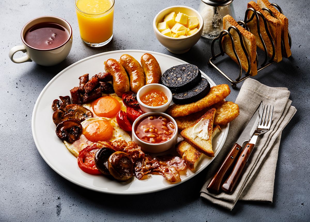 Full,Fry,Up,English,Breakfast,With,Fried,Eggs,,Sausages,,Bacon, Full fry up English breakfast with fried eggs, sausages, bacon, black pudding, beans, toasts and tea on gray concrete background