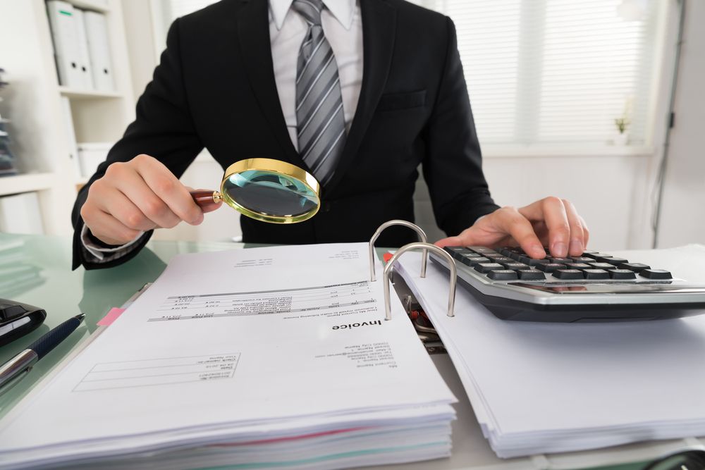 Photo,Of,Businessman,Analyzing,Bills,With,Magnifying,Glass
