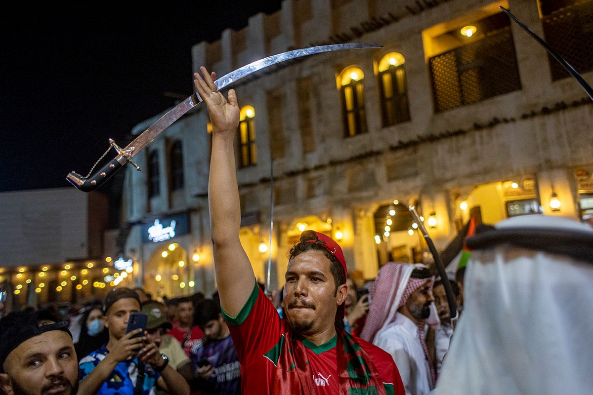 FIFA World Cup 2022 - Fans epa10352982 Fans of Morocco celebrate after Morocco won the FIFA World Cup 2022 Round of 16 match against Spain, at the Souq Waqif market in Doha, Qatar, 06 December 2022.  EPA/MARTIN DIVISEK