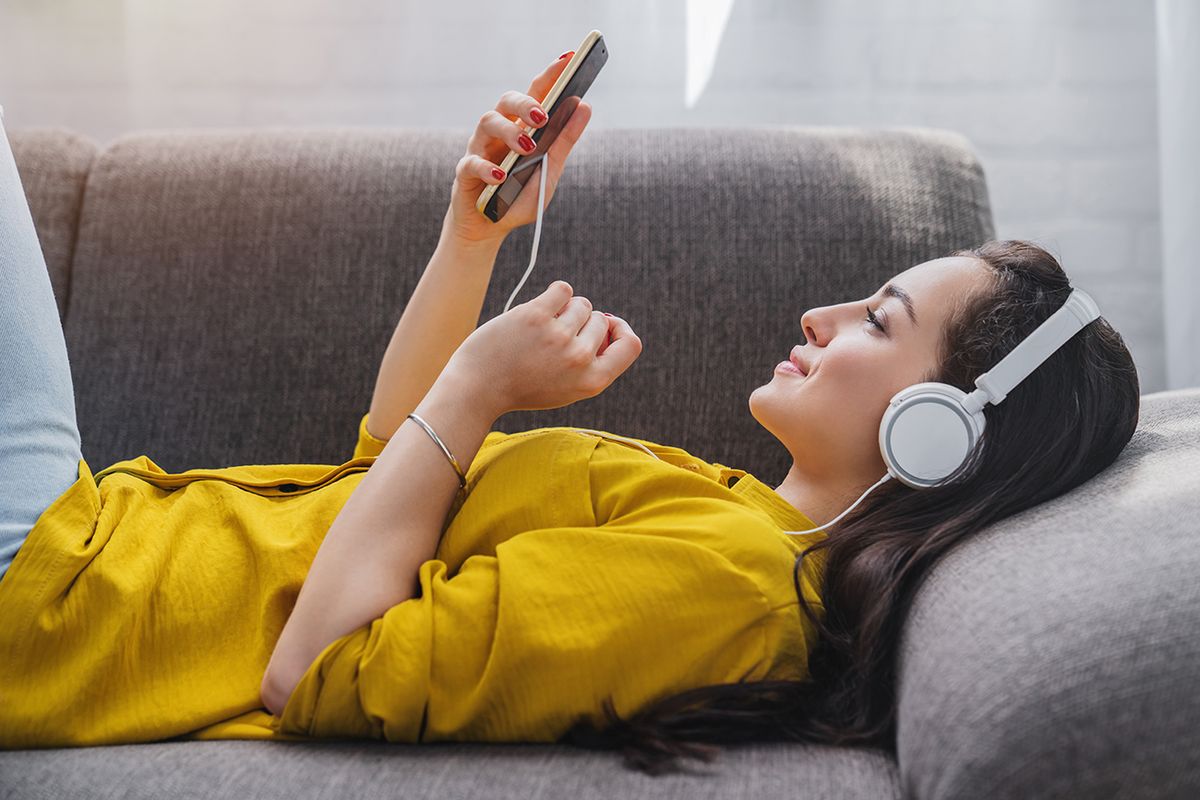 Side view of young woman listening to music online on smartphone in headphones Side view of young woman listening to music online on smartphone in headphones instagram, music, instamusic