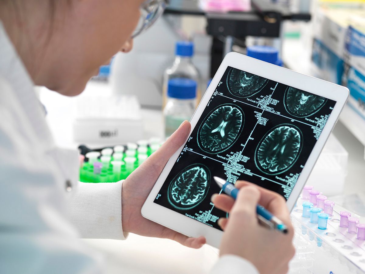 Doctor viewing patient's brain scan on digital tablet in laboratory, alzheimer