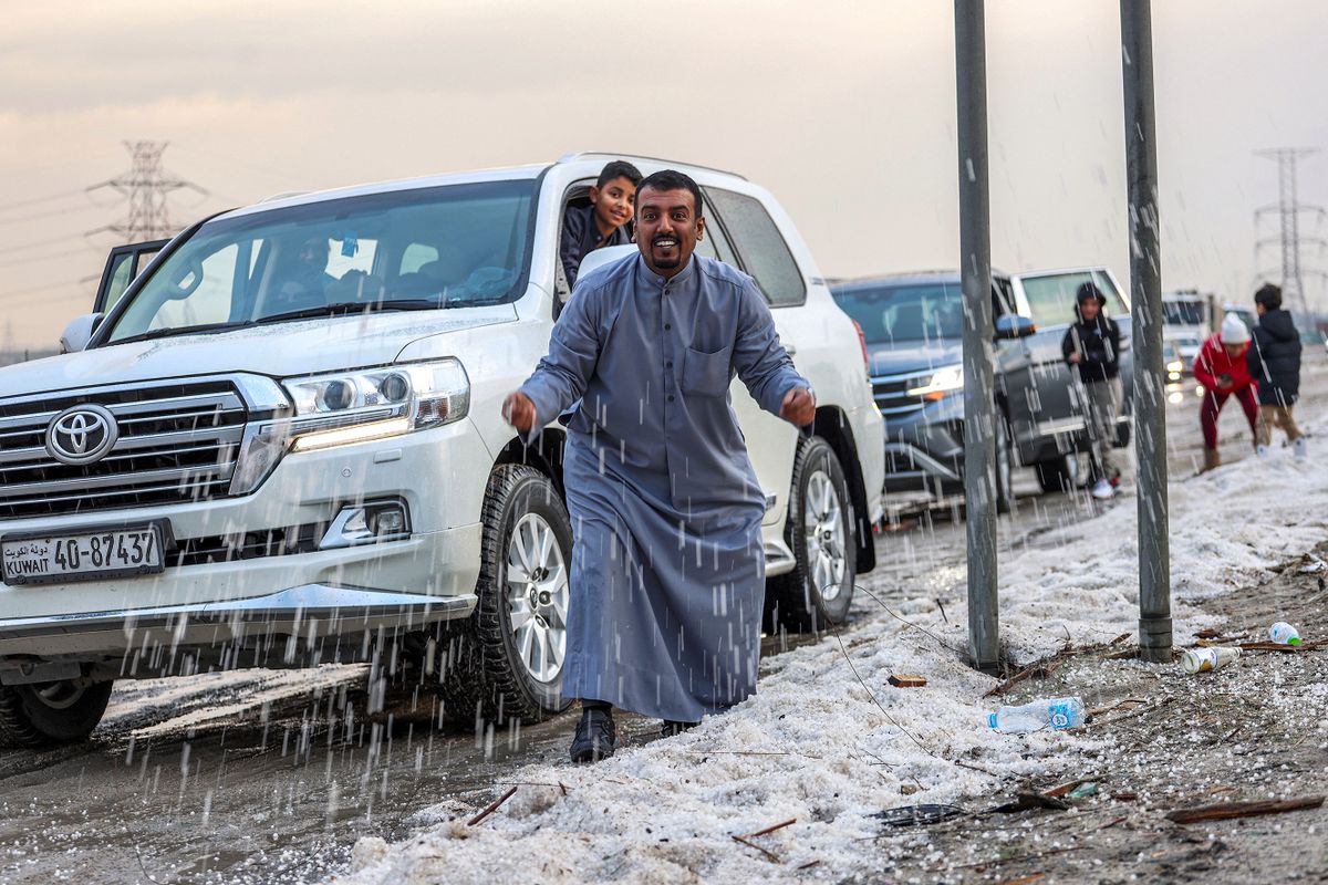 People inspect hail particles lying on the side of a road after a storm in the Umm al-Haiman district, about 55 kilometres south of Kuwait City, on December 27, 2022. - Kuwait, one of the hottest countries on Earth, has been hit by a rare hail storm that delighted children and their parents, with images of the winter white shared widely on social media on December 28. The meteorological department said precipitation had reached up to 63 millimetres but that the weather was clearing up. 