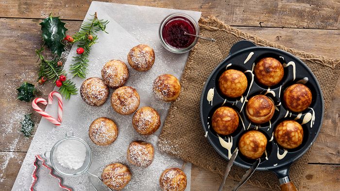 Traditional apple pancakes or Aebleskiver in danish. Traditional apple slices or aebleskiver in danish. Their name does not describe them very well. They are ball-shaped bread dough with a pancake-like texture. Traditionally eaten in the run-up to Christmas they are a Danish “comfort food” to eat in the long winter nights. A piece of apple or prune can be added to the middle of the dough halfway through cooking although this is optional, they are usually eaten with jam or fresh fruit and a dusting of icing sugar. Colour, horizontal with some copy space.