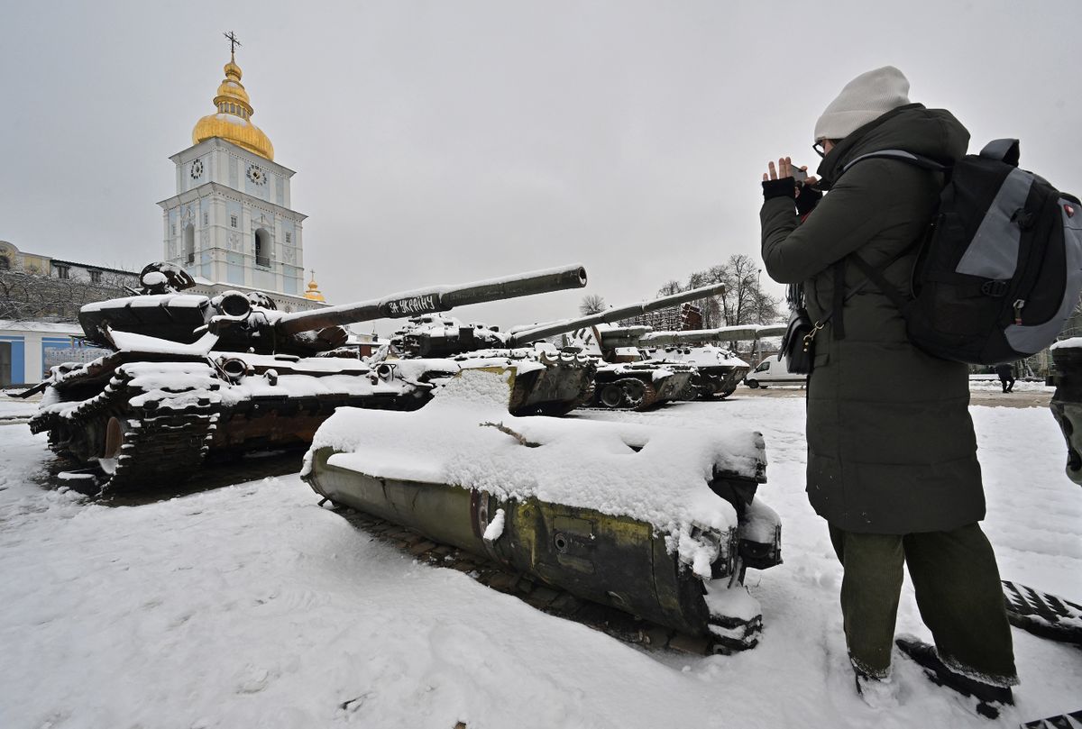 A young woman takes a picture of destroyed Russian tanks covered with snow following fresh snow fall at the open air exhibition in the Ukrainian capital Kyiv on December 12, 2022. 