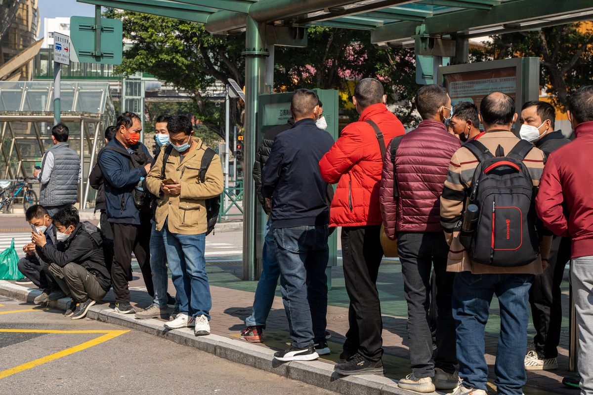 Commuters wearing face masks while waiting for a bus at a bus stop on December 29, 2022 in Macau, China.